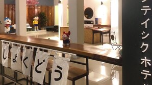 A restaurant interior with a wooden counter, white tablecloths, and a black sign with Japanese characters. - J-Boutique Hotel (Khon Kaen)