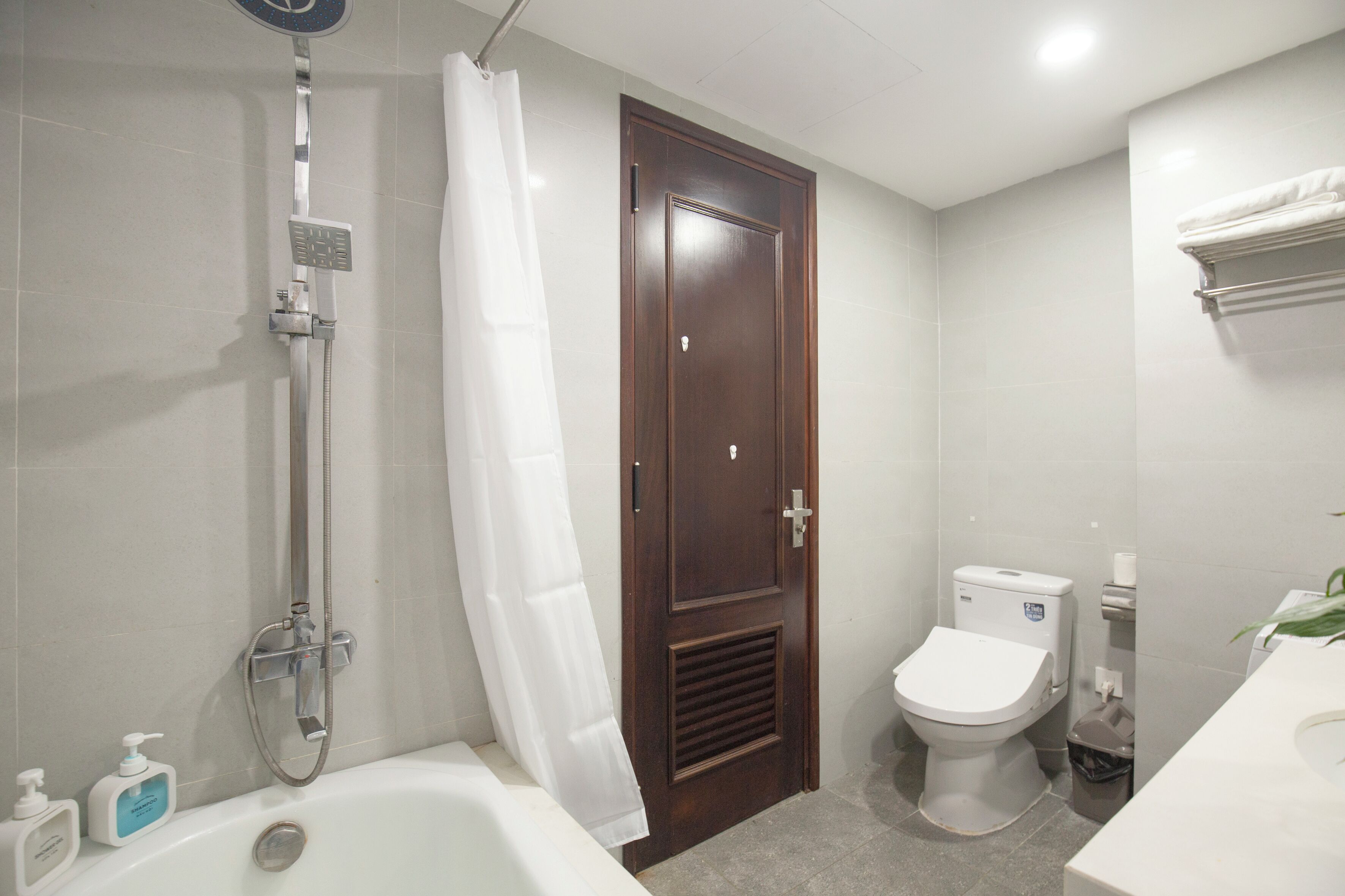 A bathroom with a bathtub, shower, toilet, and a wooden door.