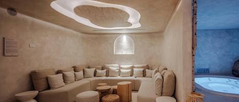 A modern, minimalist living room with a curved sofa, round ottomans, and a large window.