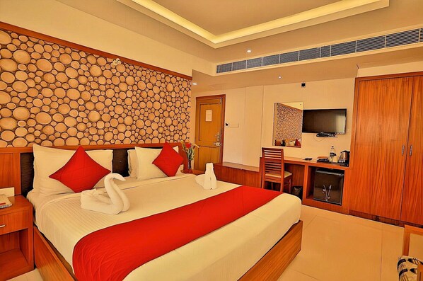 Habitación de hotel con una cama grande, un escritorio, un televisor y un armario.