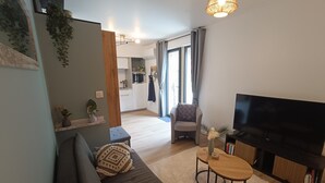 Ein modernes Wohnzimmer mit einer Couch, einem Fernseher und einem kleinen Holztisch.