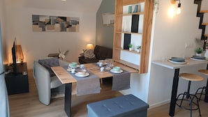 Ein modernes Wohnzimmer mit Essbereich, einer Couch, einem Couchtisch und einem Fernseher.