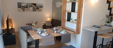 A modern living room with a dining area, a sofa, a coffee table, and a TV.