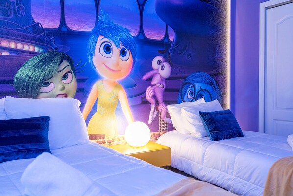 A bedroom with two beds, a nightstand, and a wall mural.