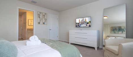 A bedroom with a bed, a dresser, a TV, and a mirror.
