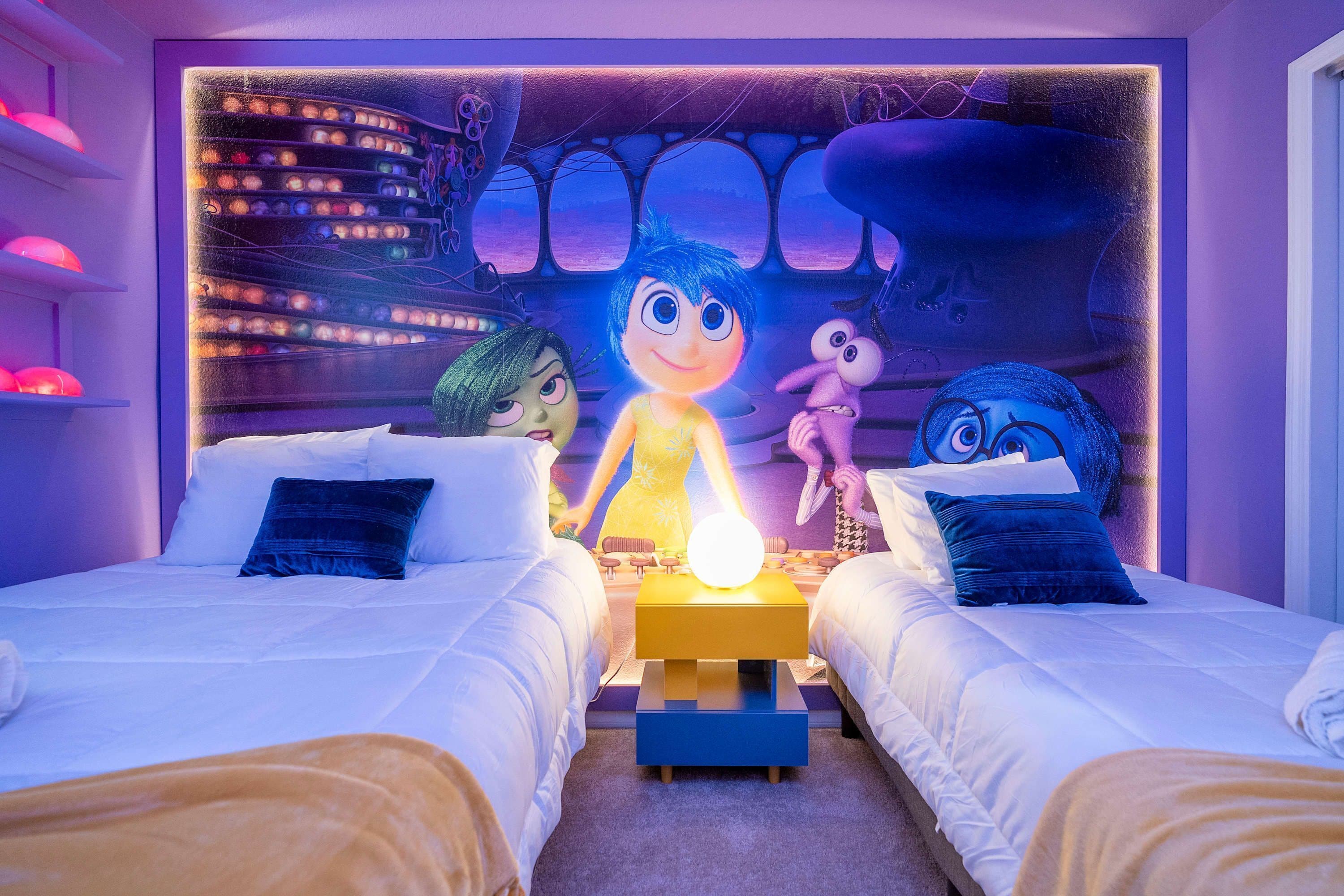 A hotel room with two beds, a large wall mural, and a unique light fixture.