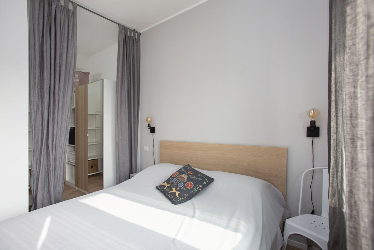 A bedroom with a bed, a nightstand, a chair, and a wardrobe.