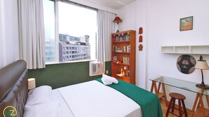 A hotel room with a bed, a desk, a bookshelf, and a window with curtains. - MZapartments Ataulfo Leblon (Rio de Janeiro)