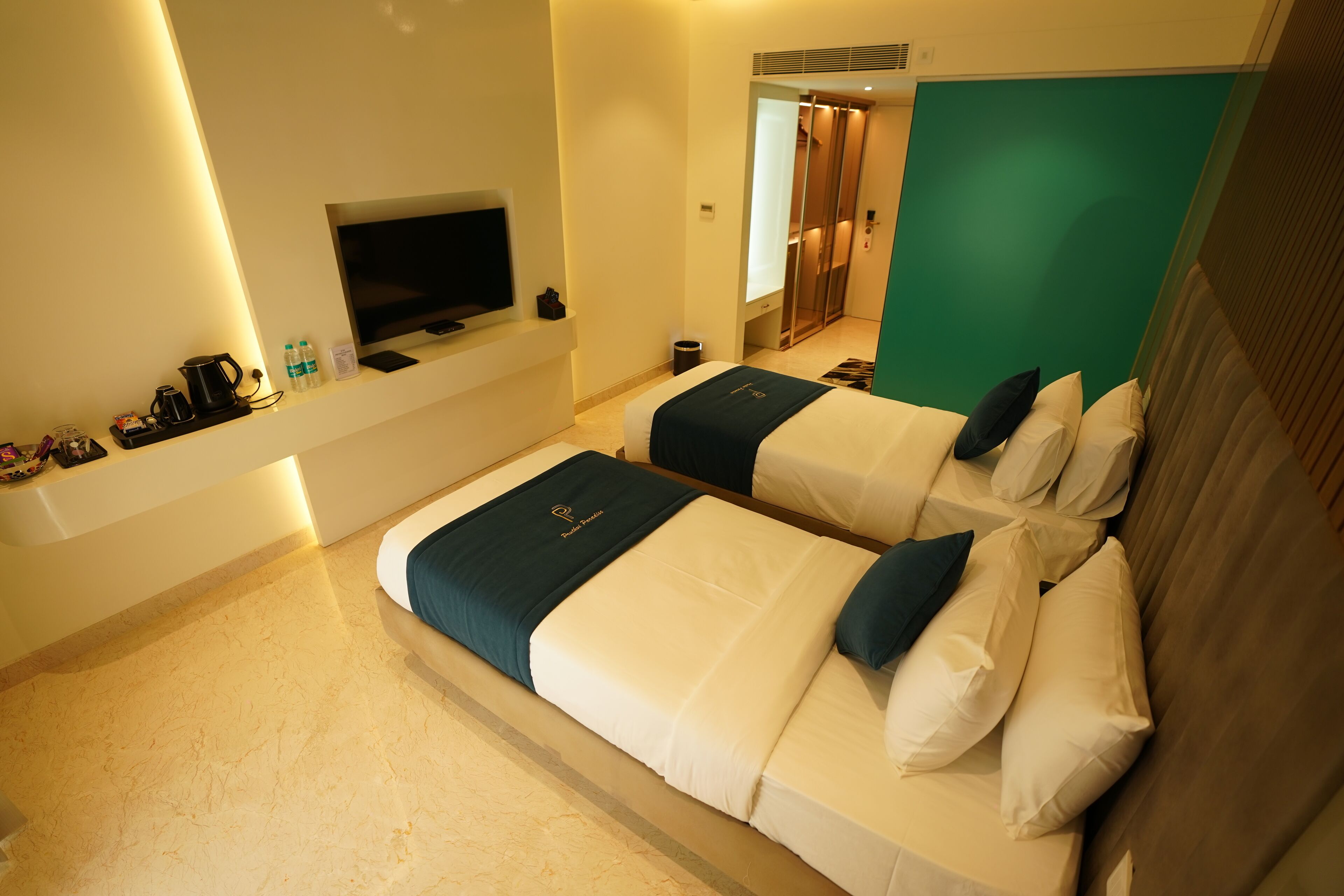 A hotel room with two beds, a TV, a coffee maker, and a small table with a tray.