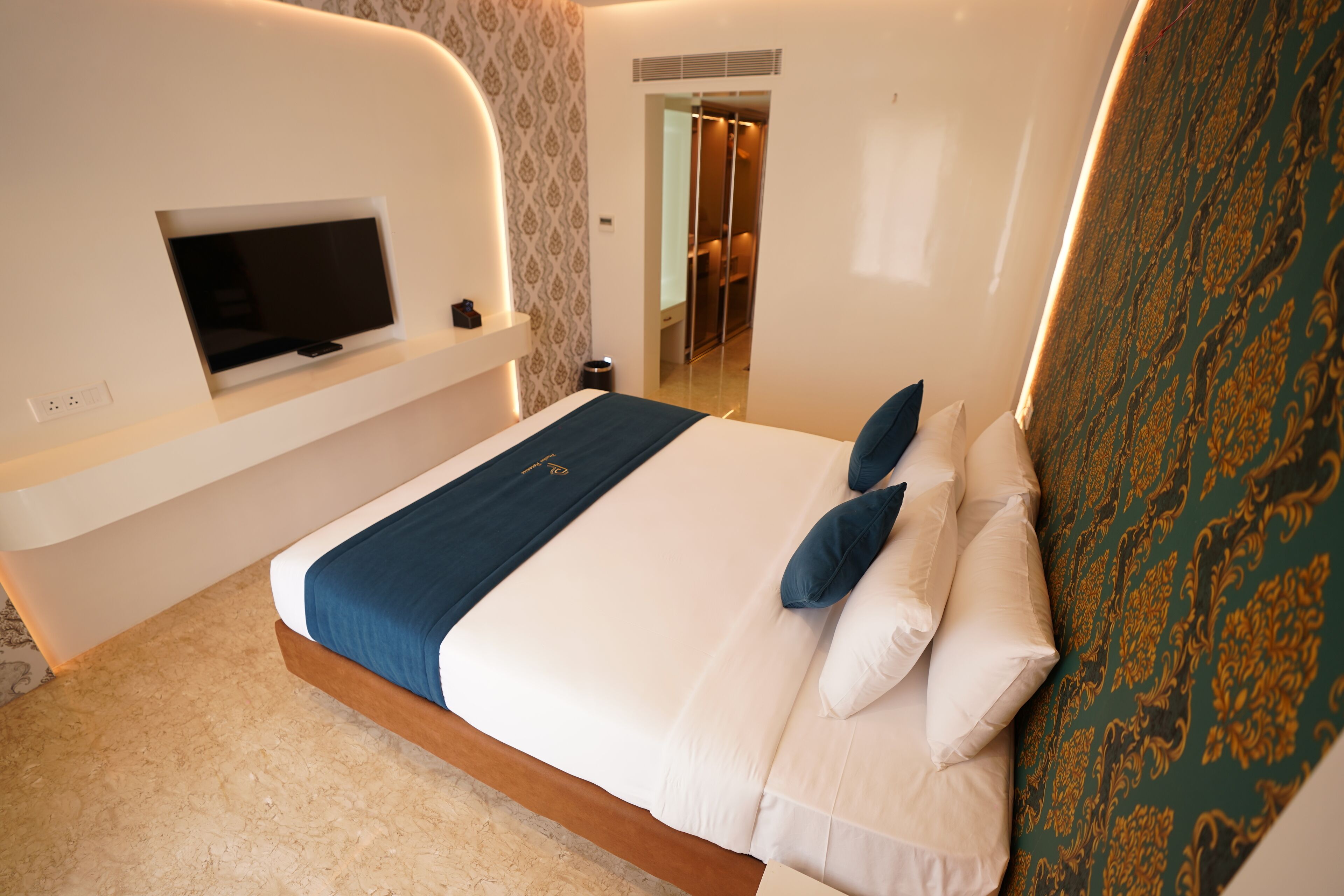 Quarto de hotel moderno com uma cama grande, televisão de tela plana na parede e closet espaçoso.