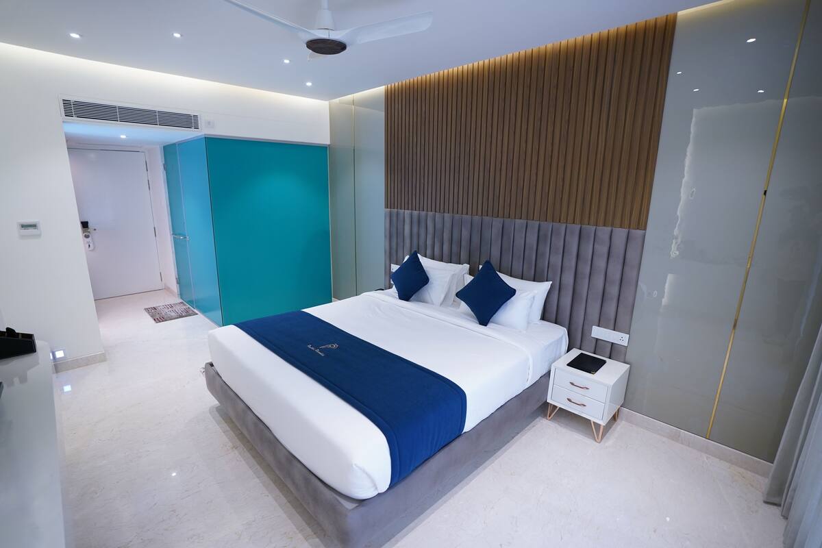 Una habitación de hotel moderna con una cama grande, una mesita de noche y un armario empotrado.