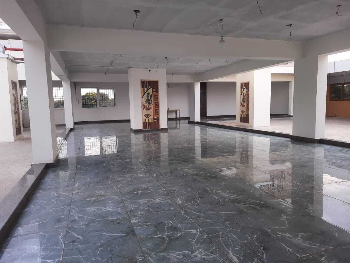 Amplio espacio interior con piso de mármol pulido, paredes blancas y ventanas grandes que dejan entrar luz natural.