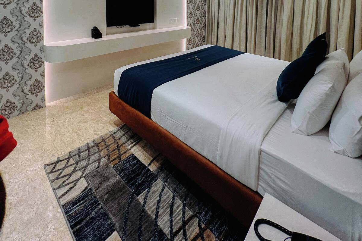 Un dormitorio moderno con televisión integrada, ventilador de techo y papel tapiz estampado.