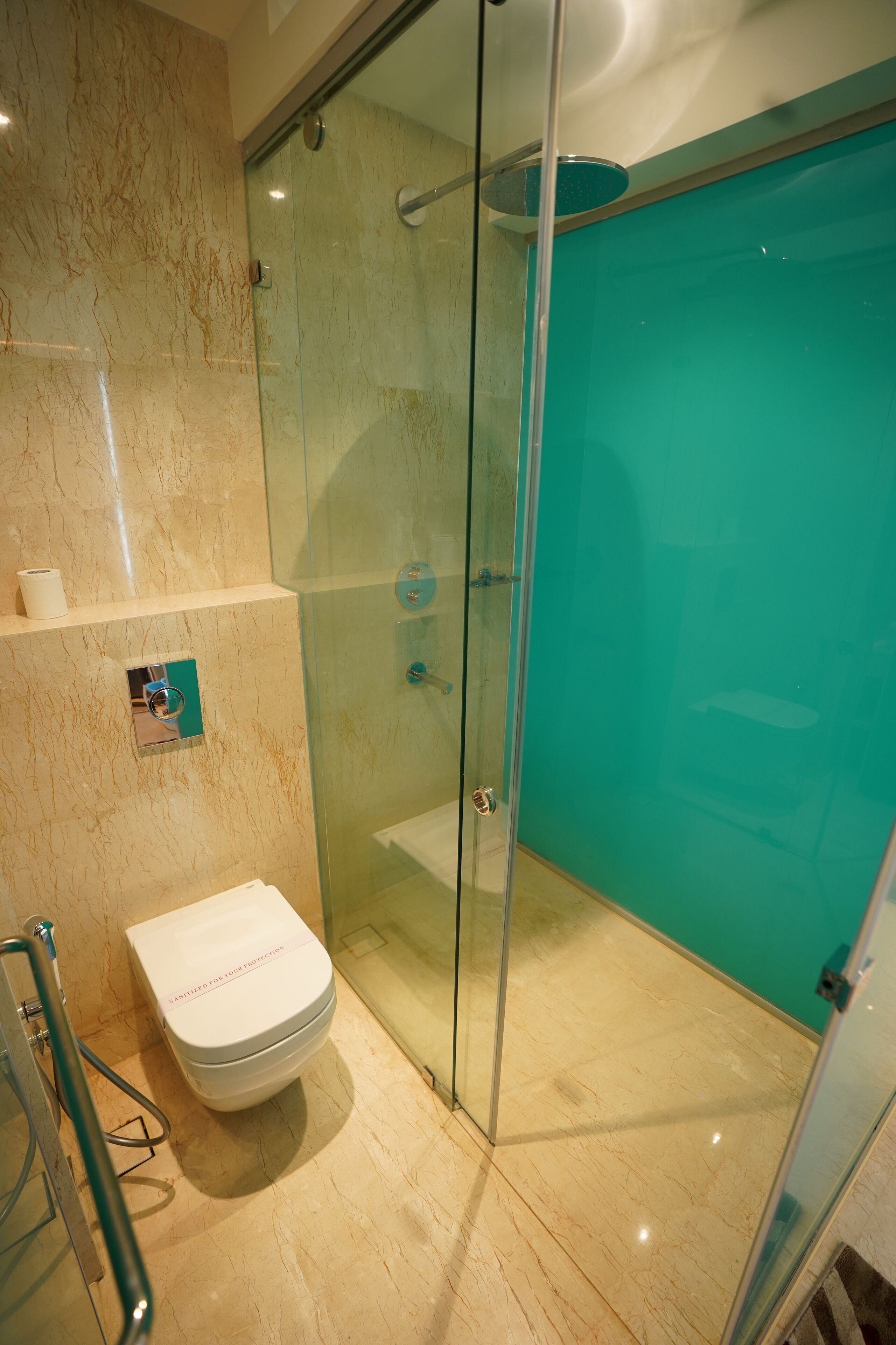 A modern bathroom with a glass-enclosed shower, a toilet, and a marble floor.