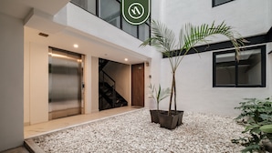 Ein moderner Gebäudeeingang mit Aufzug, Treppe und Topfpflanzen.