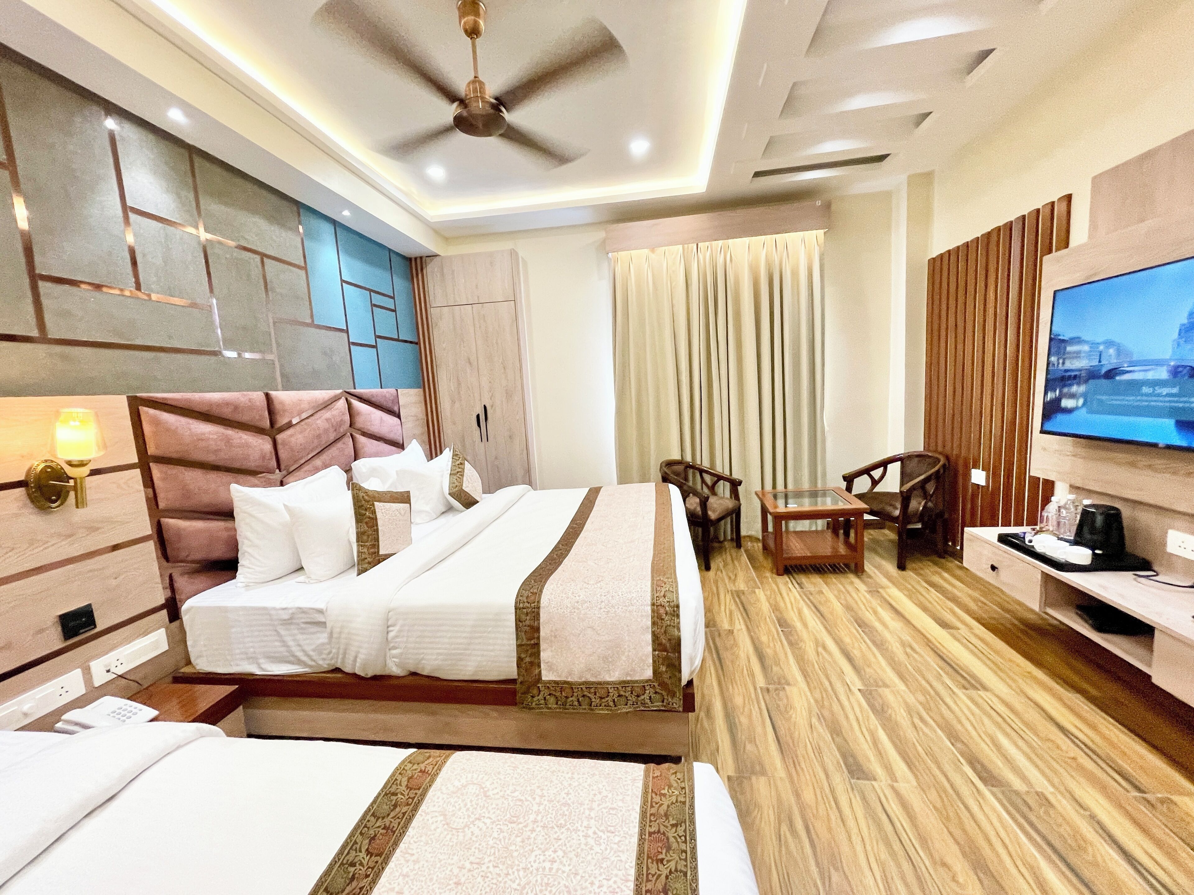 A hotel room with a large bed, a desk, a television, and a ceiling fan.