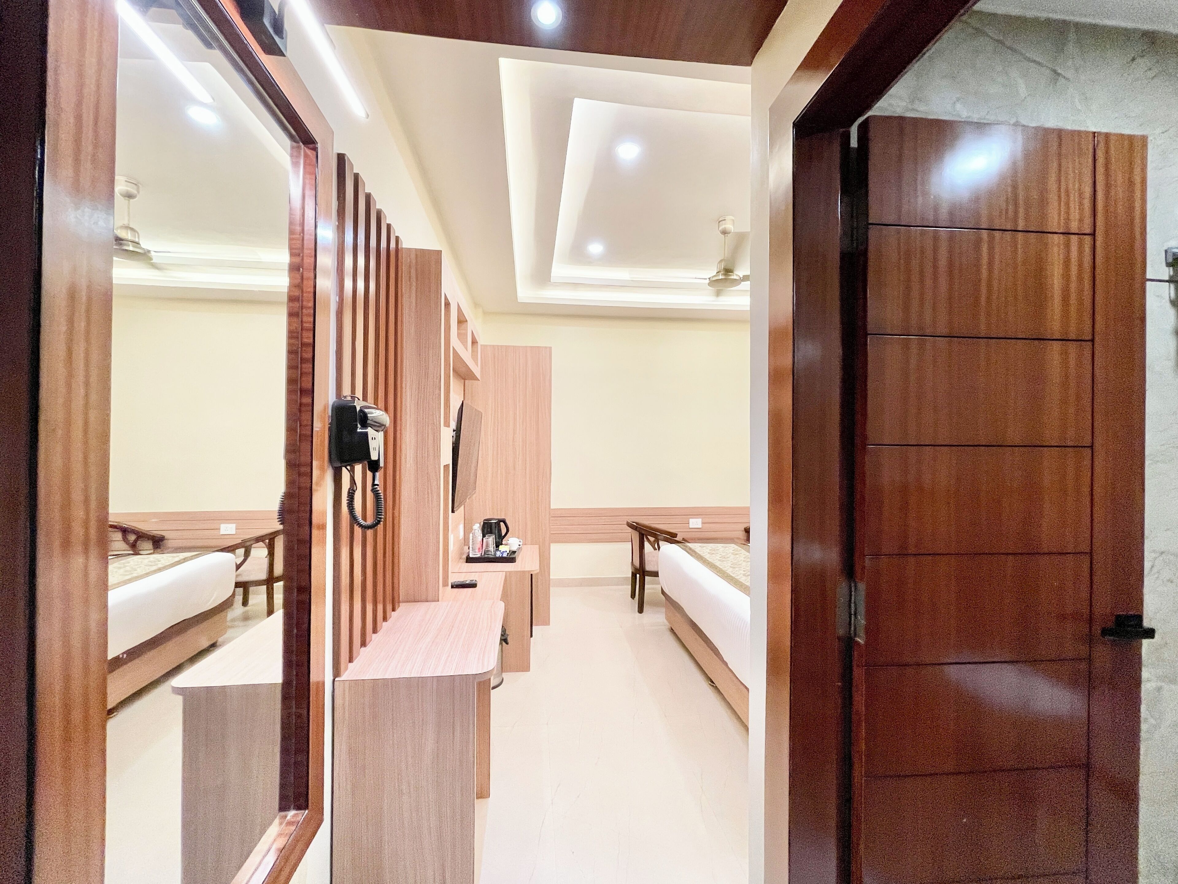 Una habitación de hotel con un mostrador de recepción de madera, teléfono, cafetera y una cama.
