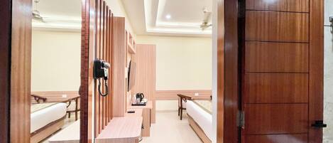 Una habitación de hotel con un mostrador de recepción de madera, teléfono, cafetera y una cama.