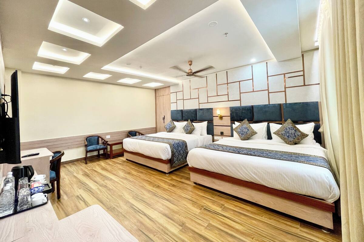 A hotel room with two beds, a desk, and a chair.