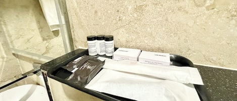 Un meuble de salle de bain avec des articles de toilette, une serviette et un bonnet de douche.