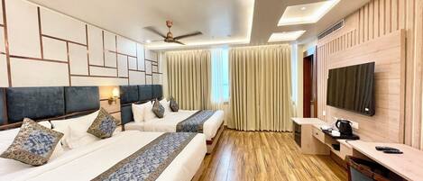 A modern hotel room with two beds, a ceiling fan, a flat-screen TV, a desk, and a coffee maker.