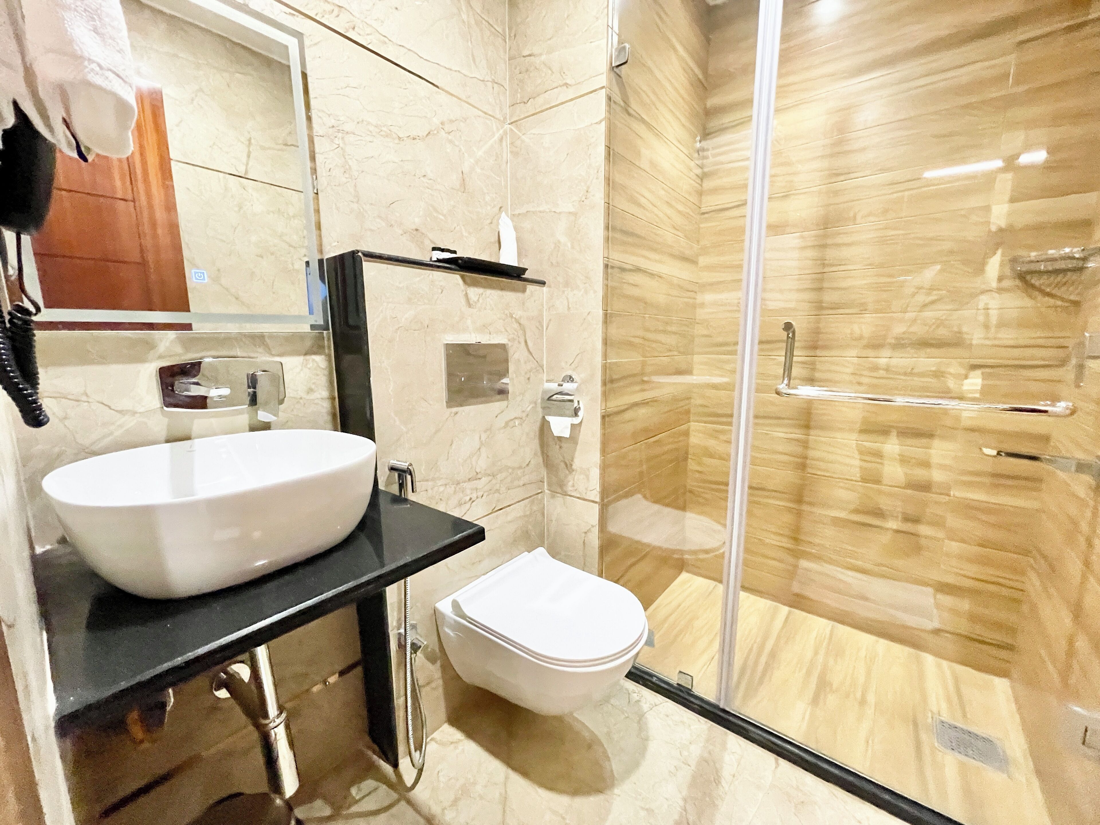 Un baño moderno con un lavabo blanco grande, un inodoro y una ducha con cerramiento de vidrio.