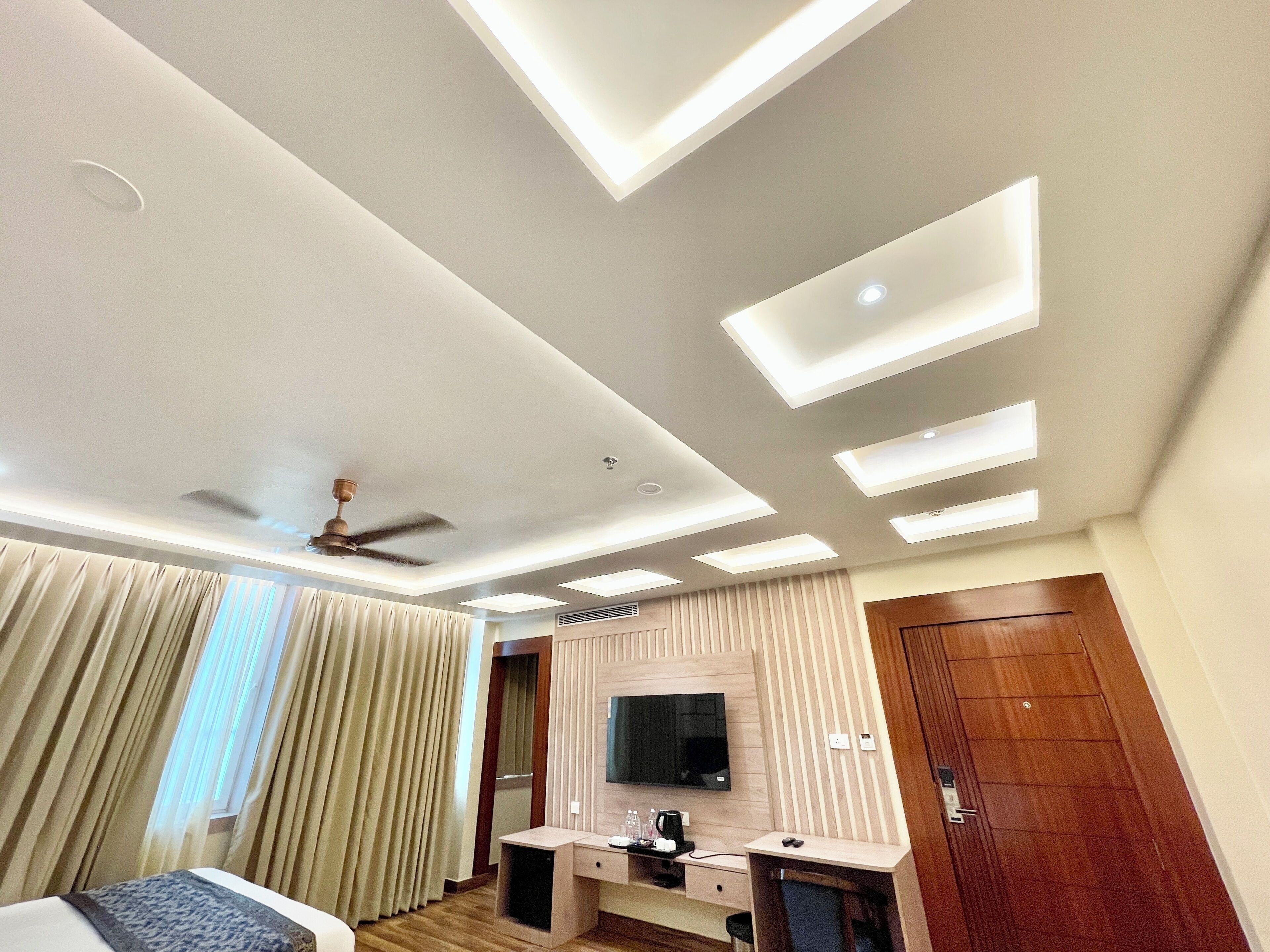 A hotel room with a bed, a desk, a television, and a ceiling fan.