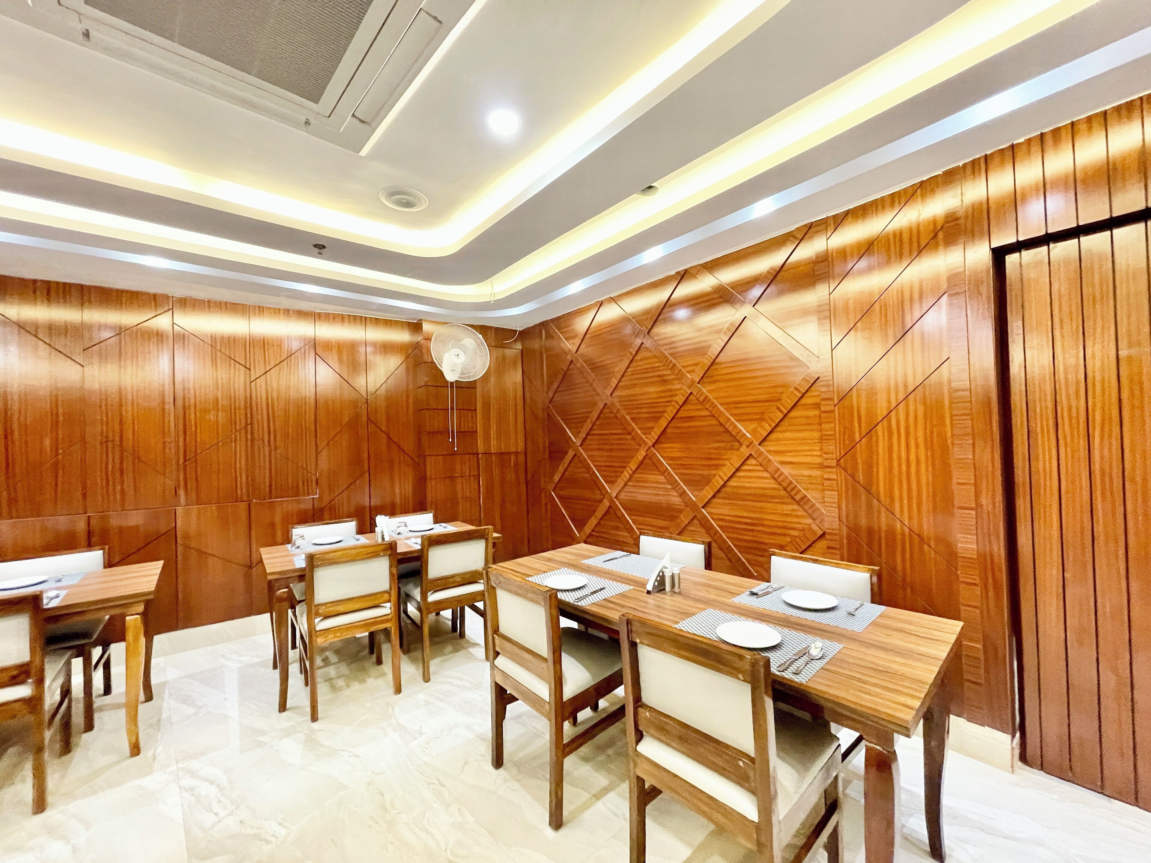 A conference room with wooden panel walls, a ceiling fan, and a long table with chairs.