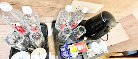 A tray with water bottles, a coffee maker, a tea set, and some snacks.