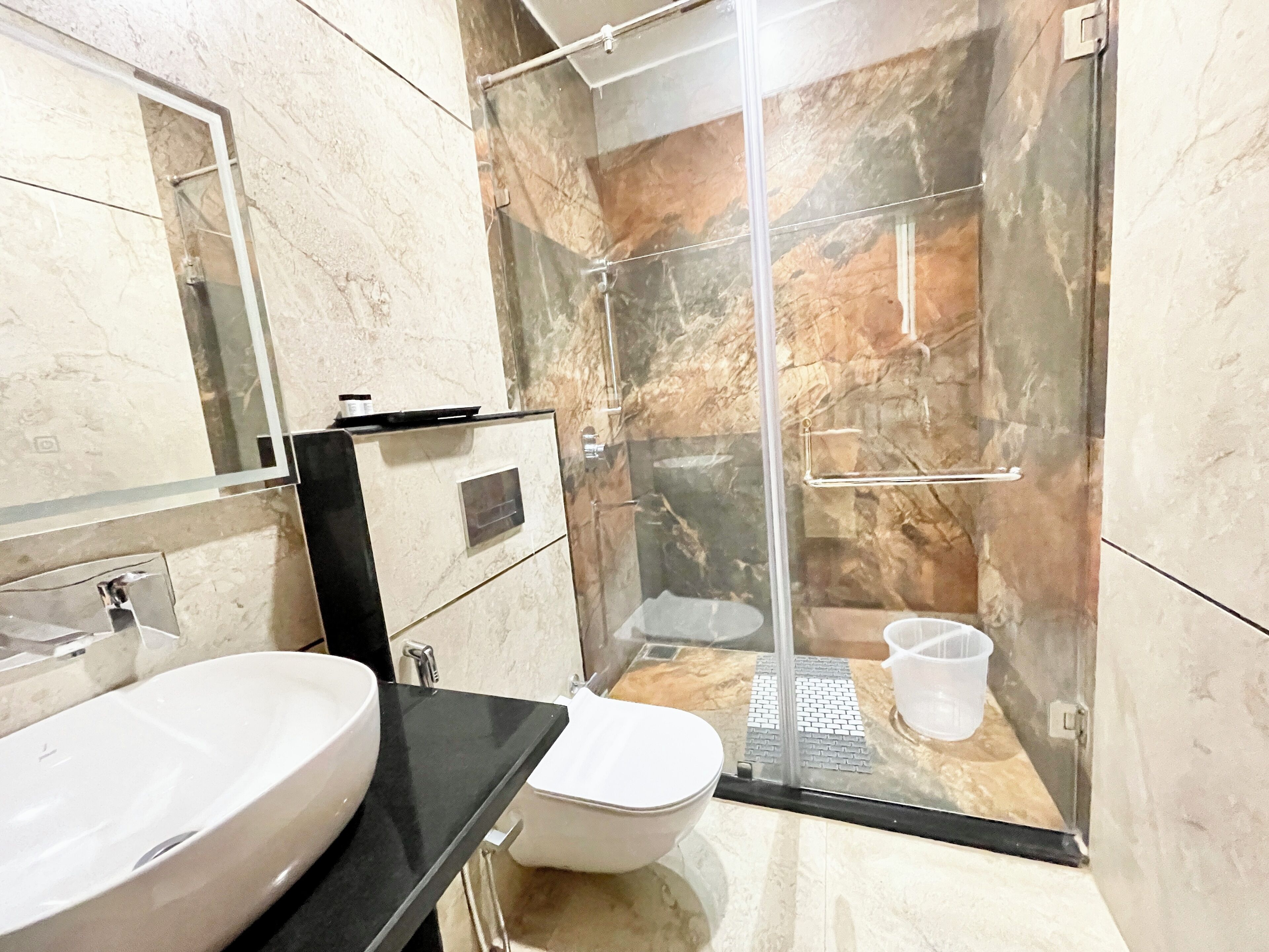 A bathroom with a glass-enclosed shower, a white sink, and a toilet.