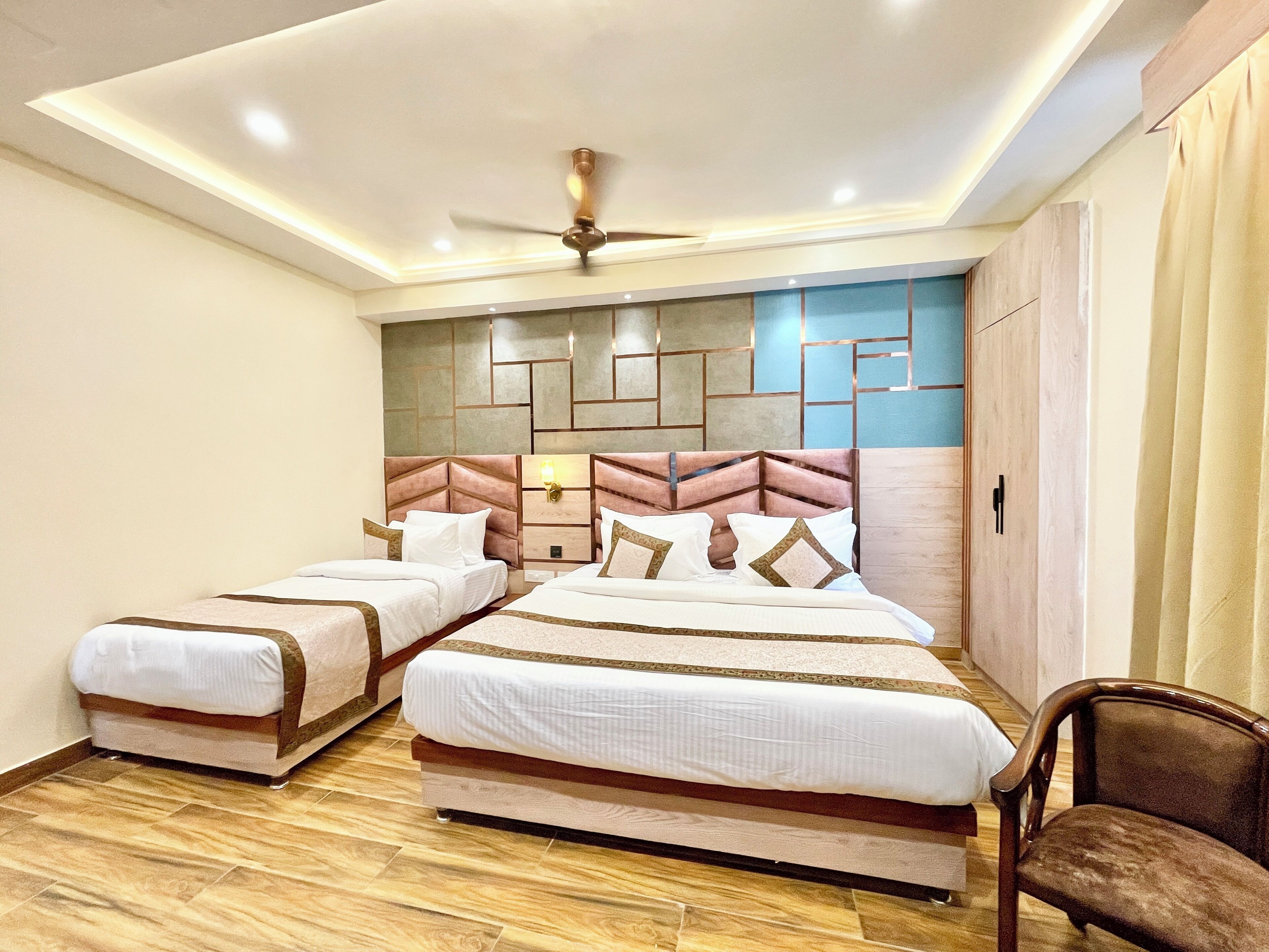 A hotel room with two beds, a ceiling fan, and a wooden floor.