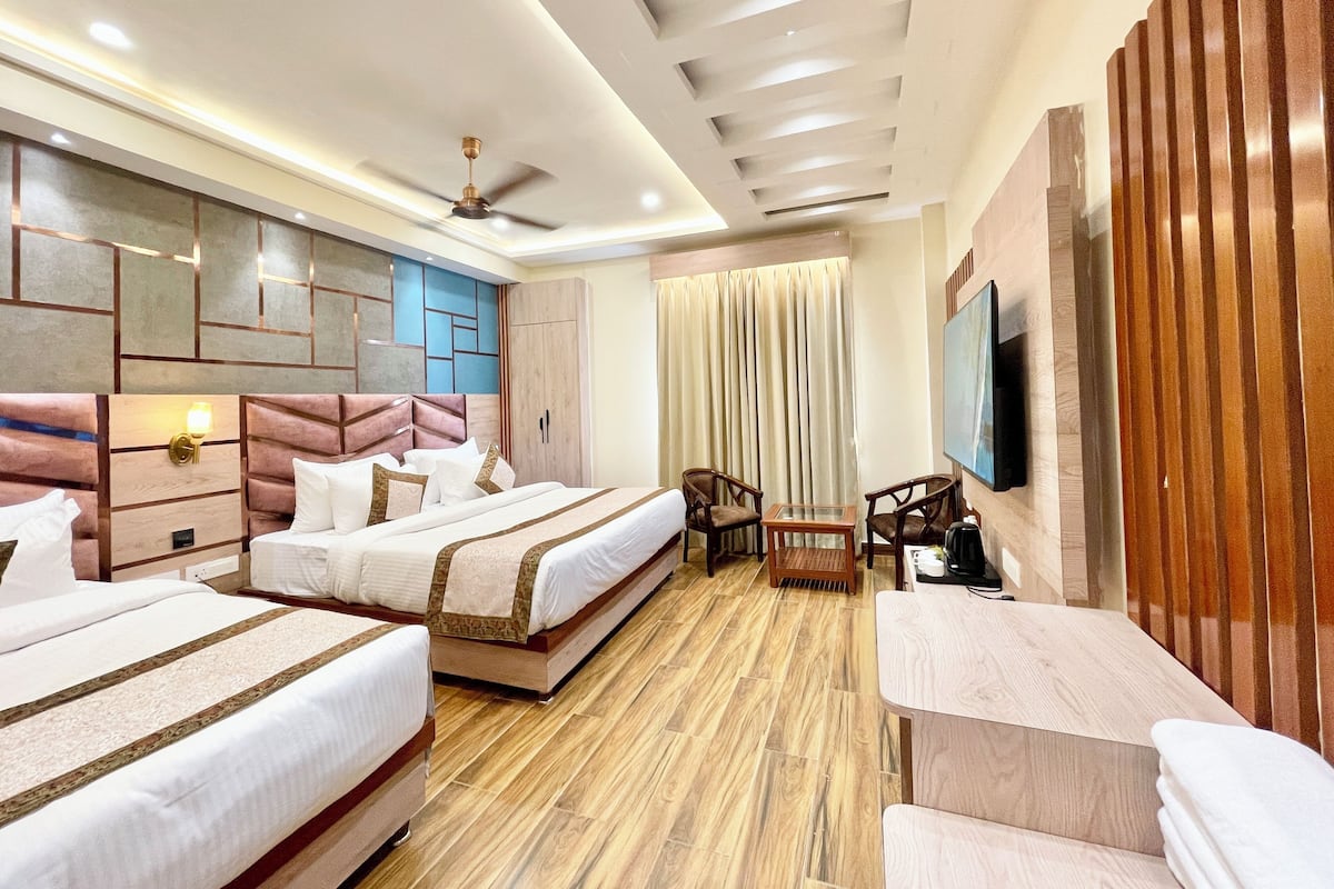 A hotel room with two beds, a ceiling fan, a TV, and a wooden panel wall.