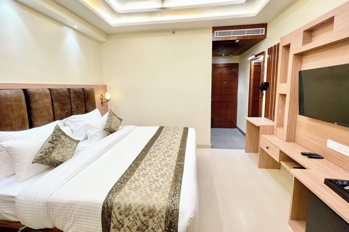 A hotel room with a large bed, a TV, and a wooden wardrobe.