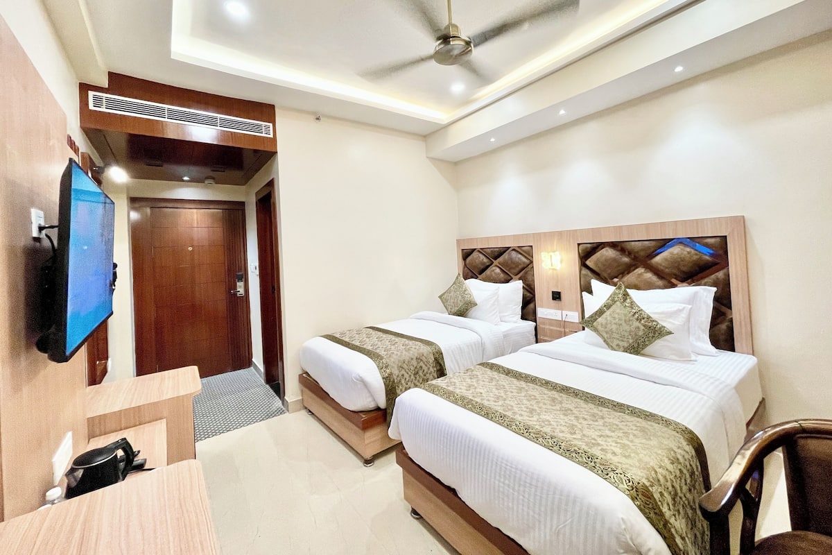 A hotel room with two beds, a TV, a ceiling fan, and a wooden headboard.