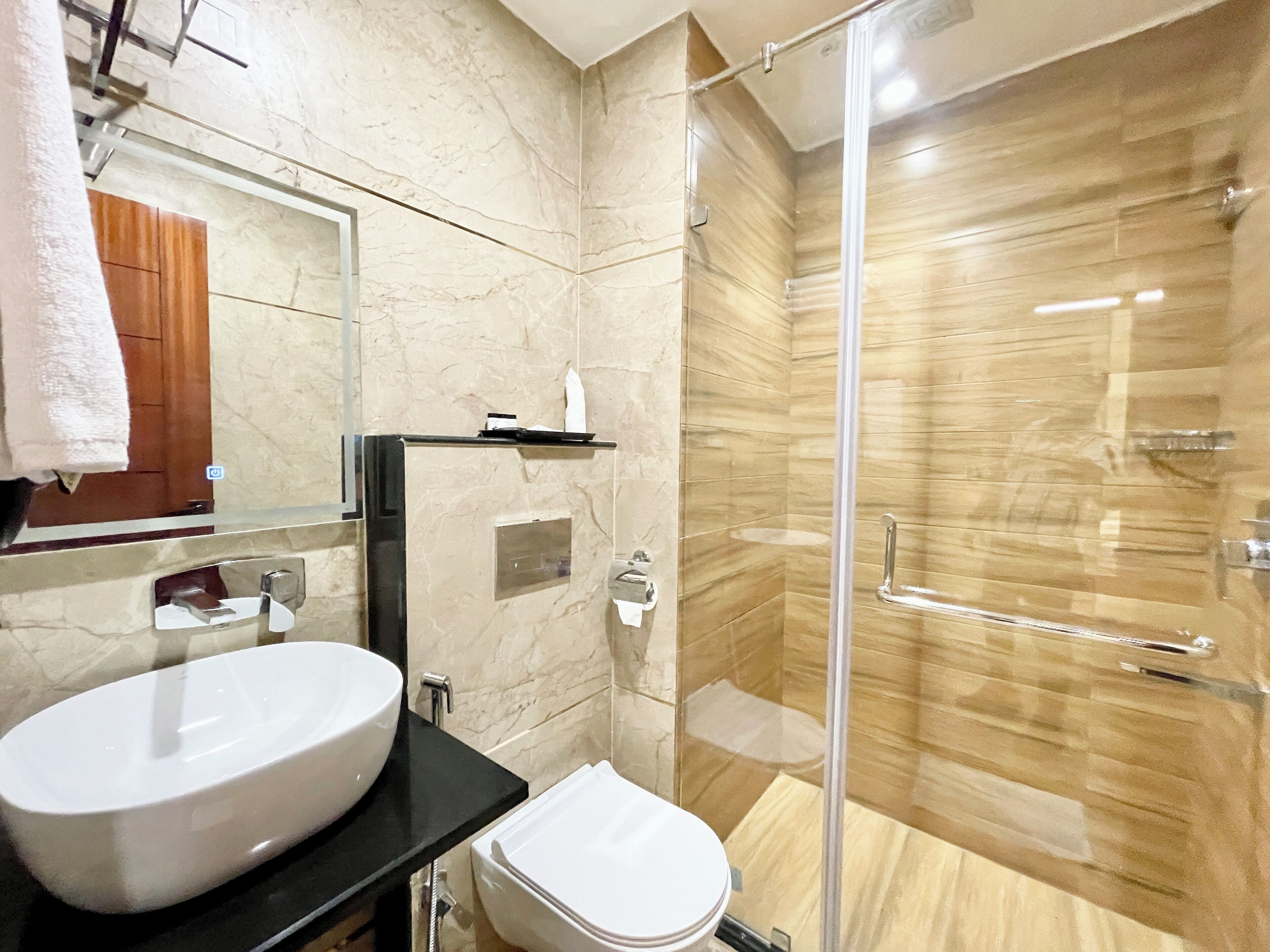 Un baño moderno con un lavamanos grande de color blanco, un inodoro y una zona de ducha con mampara de vidrio.