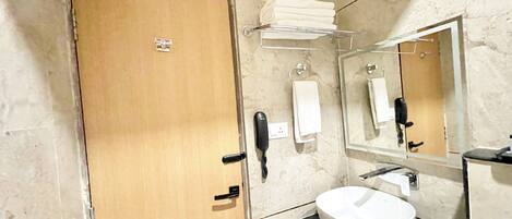 A bathroom with a wooden door, a white sink, a mirror, a towel rack, and a telephone.