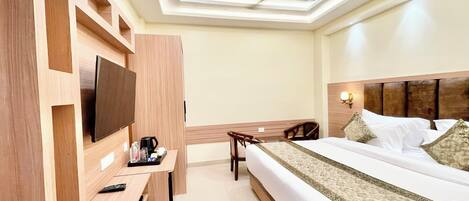 A hotel room with a bed, a desk with a TV, a ceiling fan, and a nightstand.