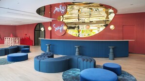 A modern lobby with a curved reception desk, blue seating areas, and a red and blue color scheme. - Riva Vibe Hotel Bangkok by PCL (Bangkok)