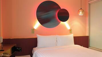 A hotel room with a bed, a desk, and a wall-mounted light fixture.