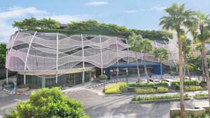 A modern building with a unique architectural design featuring a wave-like structure. - Riva Vibe Hotel Bangkok by PCL (Bangkok)
