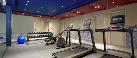 A gym with treadmills, a stationary bike, and dumbbells.