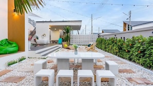 A modern outdoor patio with a white table and chairs, surrounded by pebbles and plants. - 58-20 Pool Villa (Cha-am)