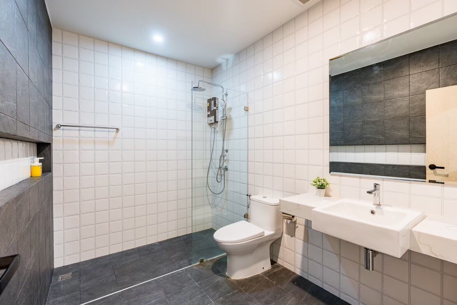 Un baño moderno con ducha envuelta en vidrio, inodoro blanco y tocador con espejo.