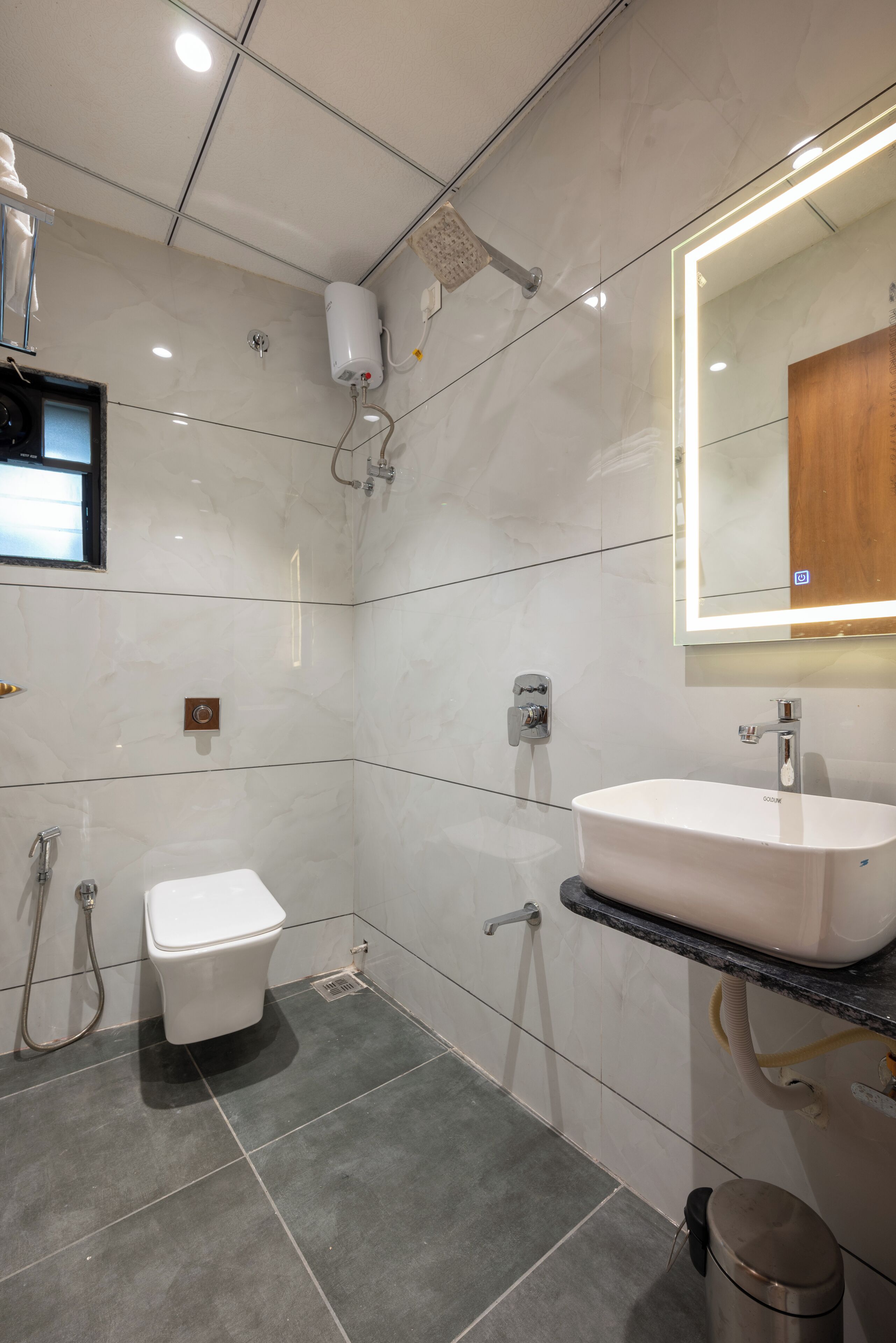 A modern bathroom with a white toilet, a sink with a mirror, and a shower area.