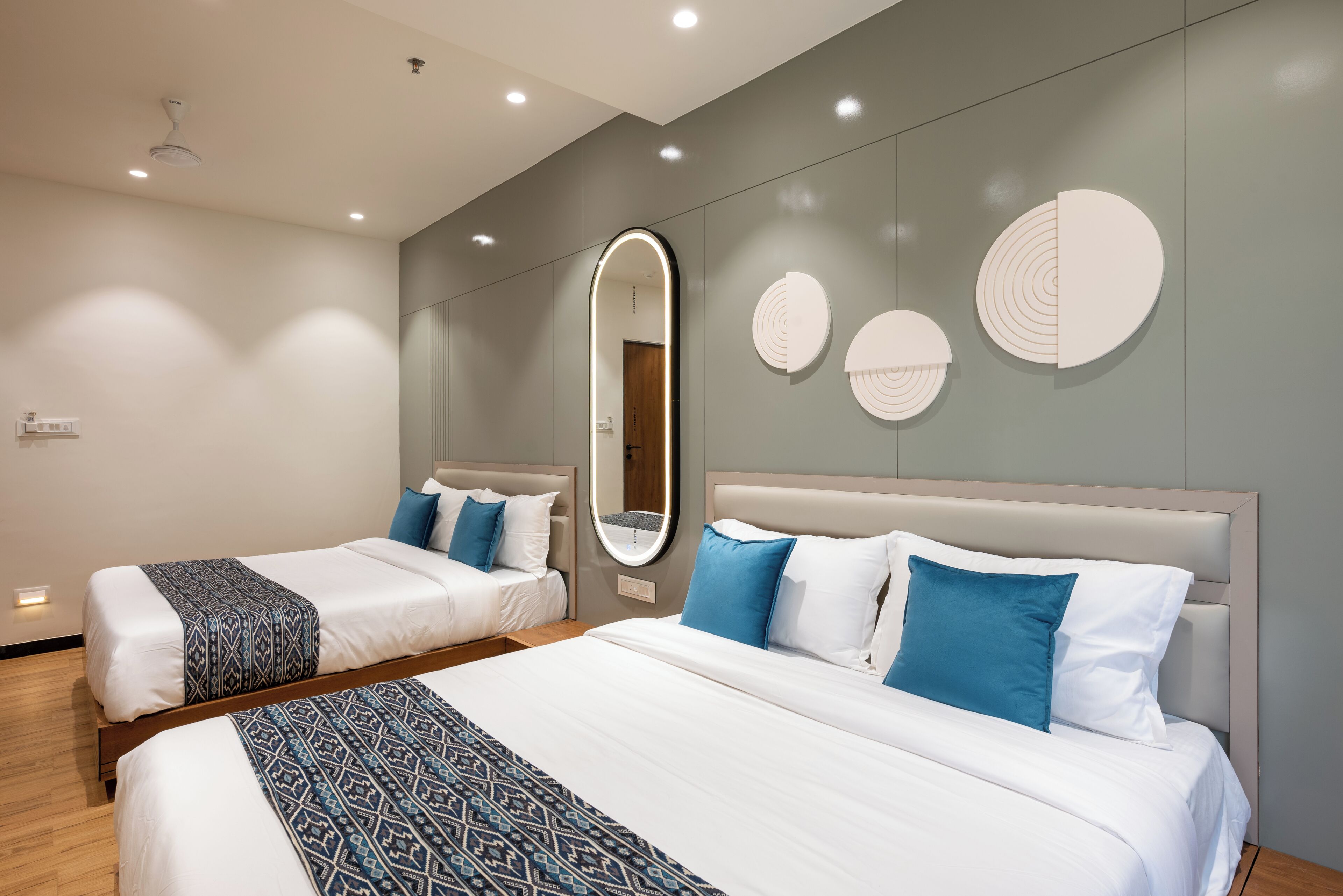 A hotel room with two beds, a large mirror, and wall-mounted circular decor.