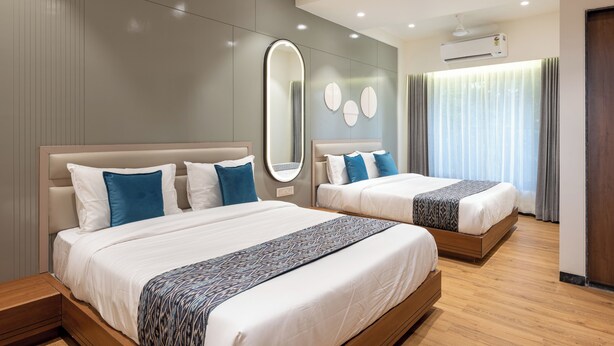 A modern hotel room with two beds, a large mirror, and a ceiling air conditioner. - The Zuree Hotel (Gandhinagar)