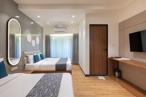 A modern hotel room with two beds, a large mirror, a TV, and a wooden floor. - The Zuree Hotel (Gandhinagar)