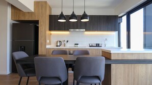A modern kitchen with a dining area, featuring a built-in refrigerator, a large island with a sink, and pendant lighting. - w* | Exlusive 3BR w/ Balcony Near Larcomar (Miraflores)