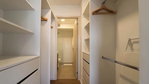 A narrow hallway with white walls, wooden flooring, and a door leading to a bathroom. - w* | Exlusive 3BR w/ Balcony Near Larcomar (Miraflores)