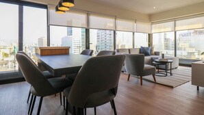 A modern interior with a dining area, sofas, and large windows offering city views. - w* | Exlusive 3BR w/ Balcony Near Larcomar (Miraflores)